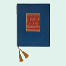 In blaues und rotes Leder gebundenes Buch mit Goldprägung auf dem Buchdeckel und goldfarbener Kordel