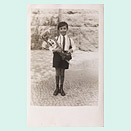A six-year-old boy in shorts holding a cone full of candy and smiling sheepishly at the camera.
