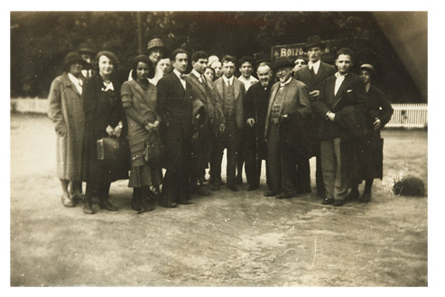 Approx. twenty young men and women and two elderly men gathered in a field for a group photo.
