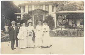 Black and white photo of two men and three women in a park in front of a house