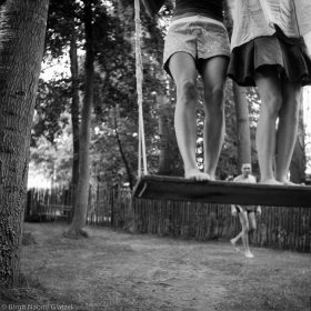 Black and white photograph of two women standing on a swing