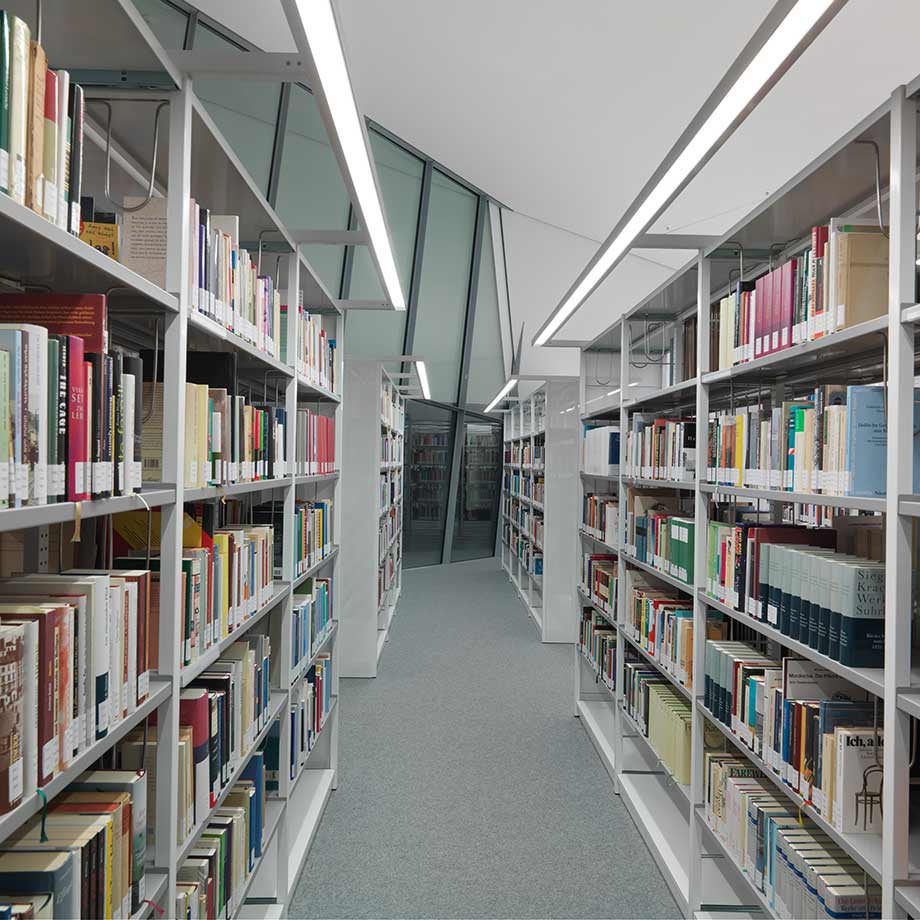 View into the aisle between two rows of bookshelves in a library