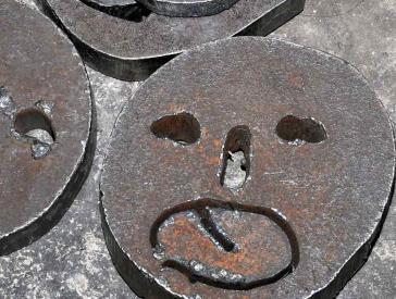 Close-up of faces cut into metal discs.