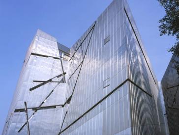 Teil der Fassade des Libeskind-Baus aus grauem Titanzink, mit sich kreuzenden und schräg verlaufenden Fenstern.