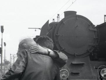 Two men hug at a train station.