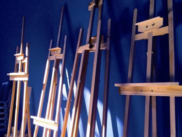 Several easels in front of a dark blue wall