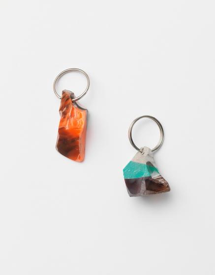 Two small brightly colored mineral or rock like objects with a keychain ring in each one