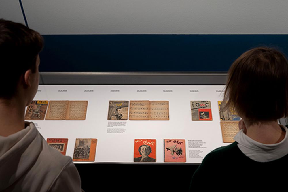 Room view of the exhibition "Het Onderwater Cabaret": two visitors look at documents in a display case.