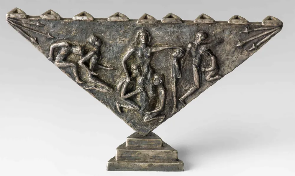 Dreieckiger Leuchter aus Bronze, der auf der Spitze steht. Darauf sind eine Frau und sieben Männer in kauernder, klagender bzw. trauernder Haltung zu sehen. Die Darstellung ist angelehnt an die Märtyrergeschichte von Channa und ihren sieben Söhnen.