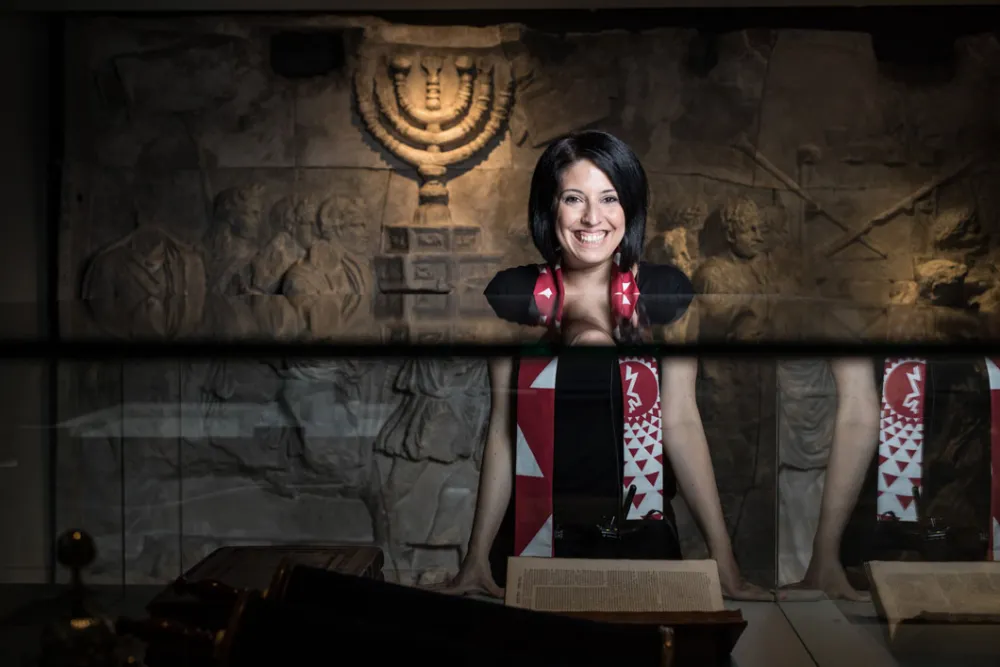A laughing woman standing in a room of the exhibition “Welcome to Jerusalem”