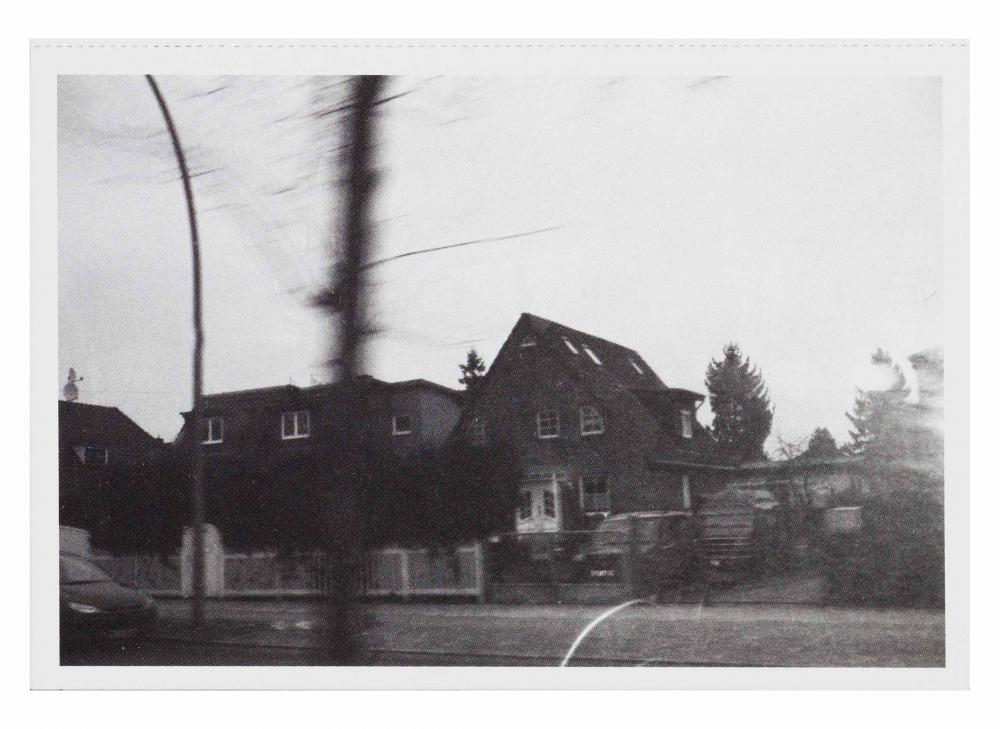 Black and white photograph of a house, the foreground is blurred as if the photographer was moving while the picture was being taken
