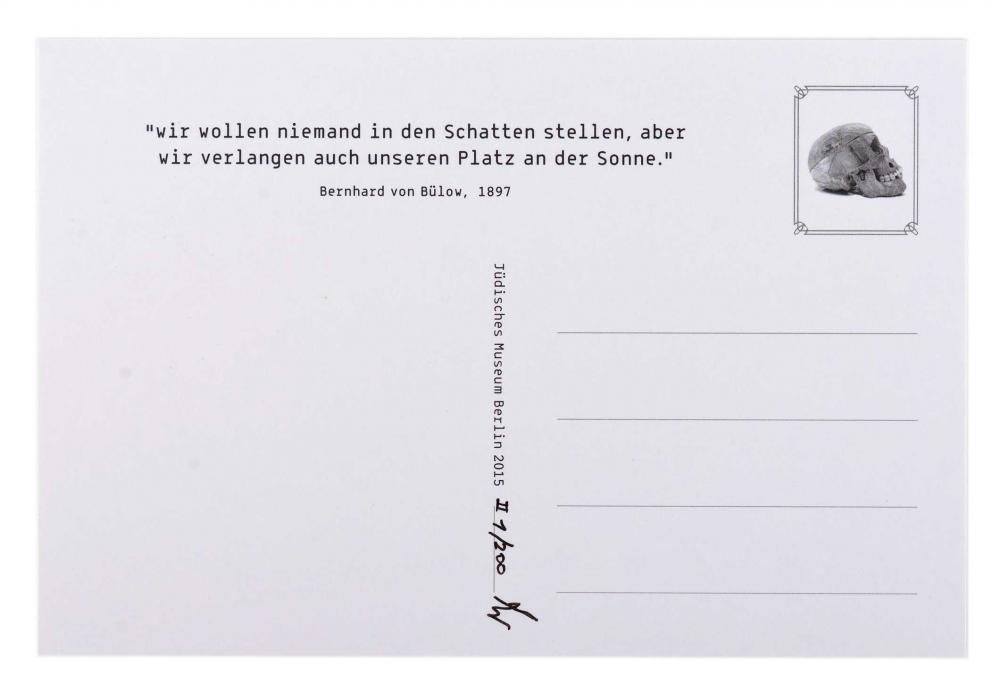 Auf der Rückseite einer weißen, unausgefüllten Postkarte befindet sich oben ein Zitat und an der Stelle der Briefmarke das Bild eines Totenkopfes.