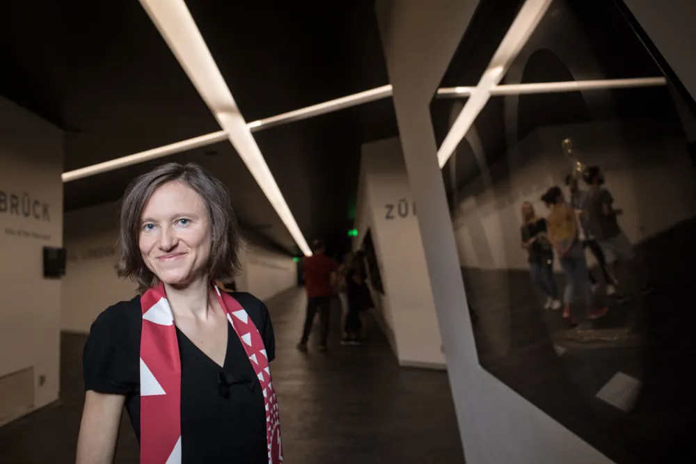 A woman stands in front of a showcase in the axles of the Libeskind building