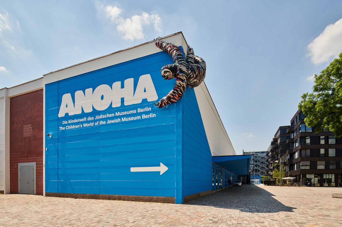 ANOHA lettering on a wall with a sloth hanging out made out of bicycle parts
