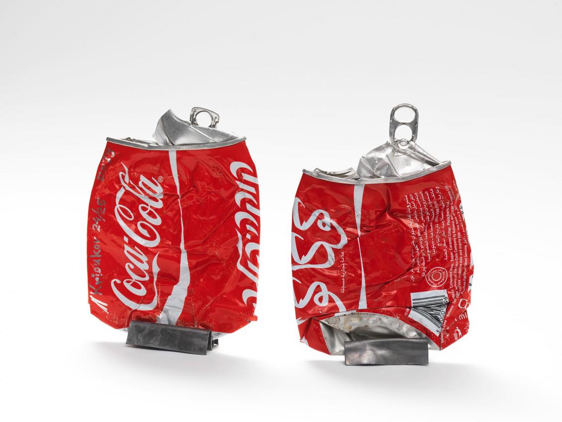 Two flattened red aluminum soda cans displayed vertically by two metallic clips