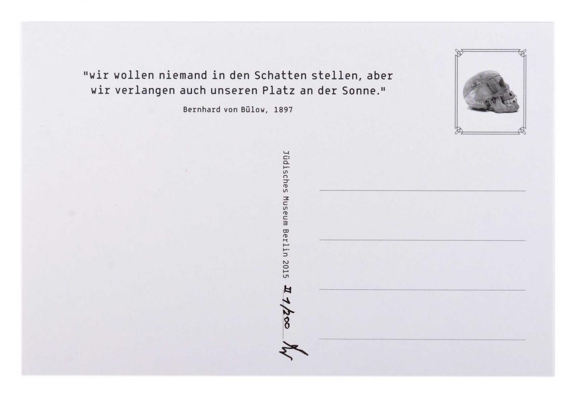 Auf der Rückseite einer weißen, unausgefüllten Postkarte befindet sich oben ein Zitat und an der Stelle der Briefmarke das Bild eines Totenkopfes.