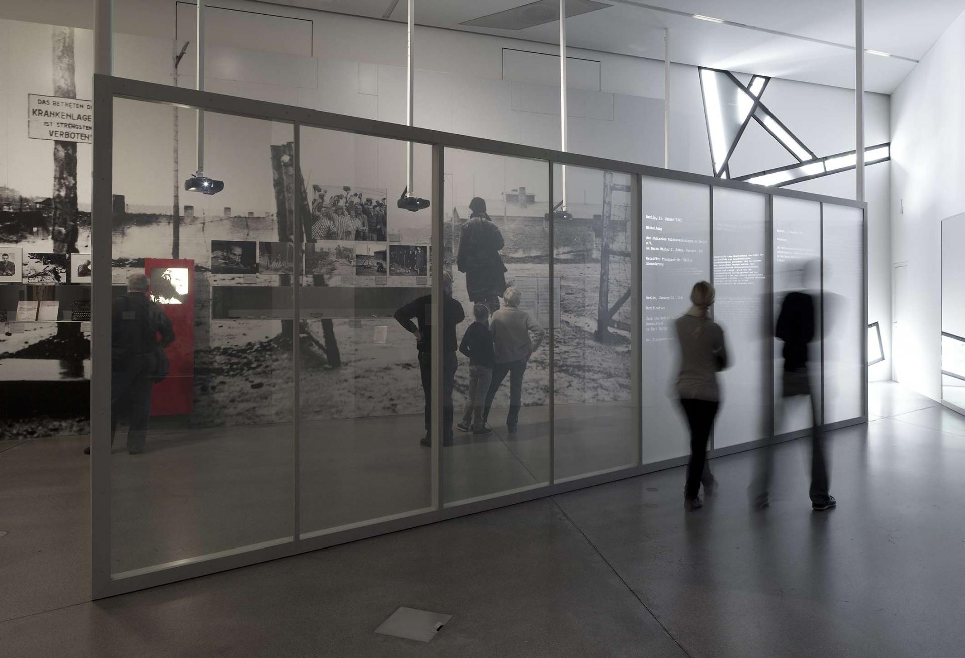 Visitors walk by in a blur while reading text on a wall in the permanent exhibition