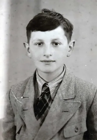 Black and white photo: Portrait of a dark-haired boy. He looks friendly into the camera.