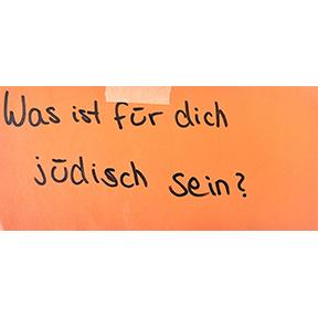 Handschrift Schwarz auf Orange: Was ist für dich Jüdischsein?