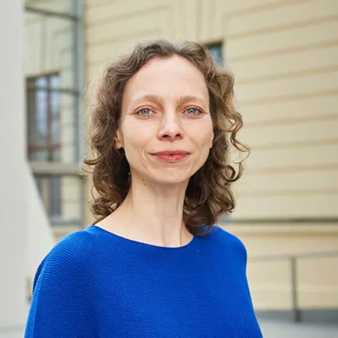 Portrait photo of a smiling woman wearing a bright blue jumper: she looks directly into the camera.