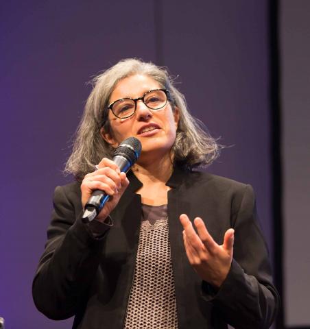 Portrait photo of woman (Rosa Fava) with microphone in hand.