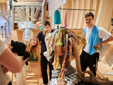 Three adults examine an animal sculpture.