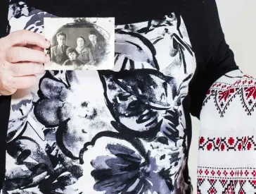 An elderly lady holding an embroidered wedding scarf and a black and white photograph in her hands.