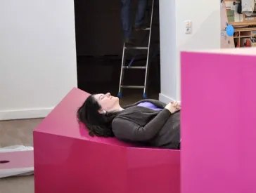 The curator Michal Friedlander lying on a showcase.