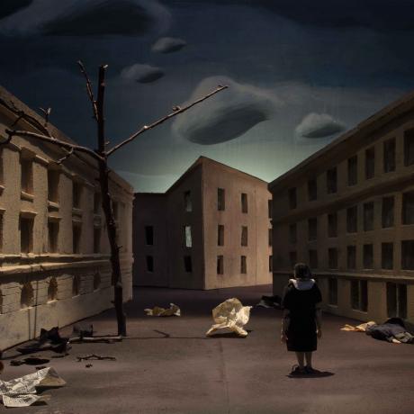 Still from the animated film “The Lemberg Machine”. A female figure stands with her back to the camera in a deserted, gloomy street.