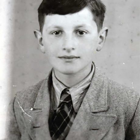 B&W photo: Portrait of a dark-haired boy. He looks friendly into the camera.