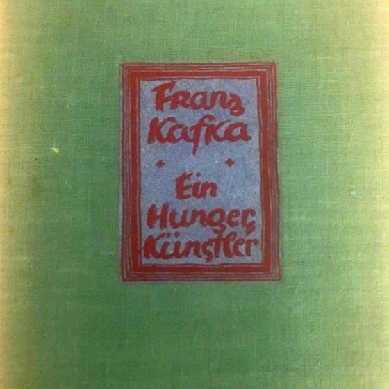 Detail of a green book cover with a glued-on, red-framed label with the inscription: “Franz Kafka, Ein Hungerkünstler” (A Hunger Artist).