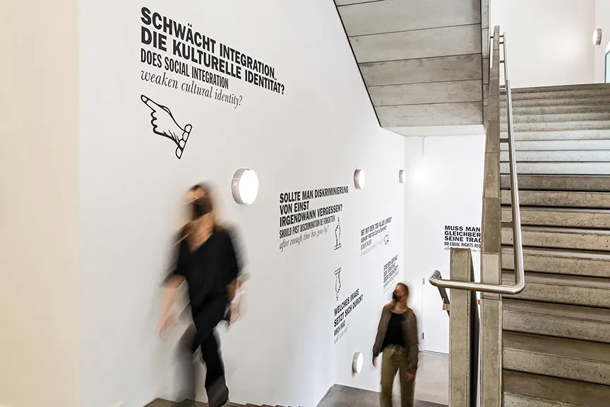Staircase with murals from the Moses Mendelssohn exhibition with visitors