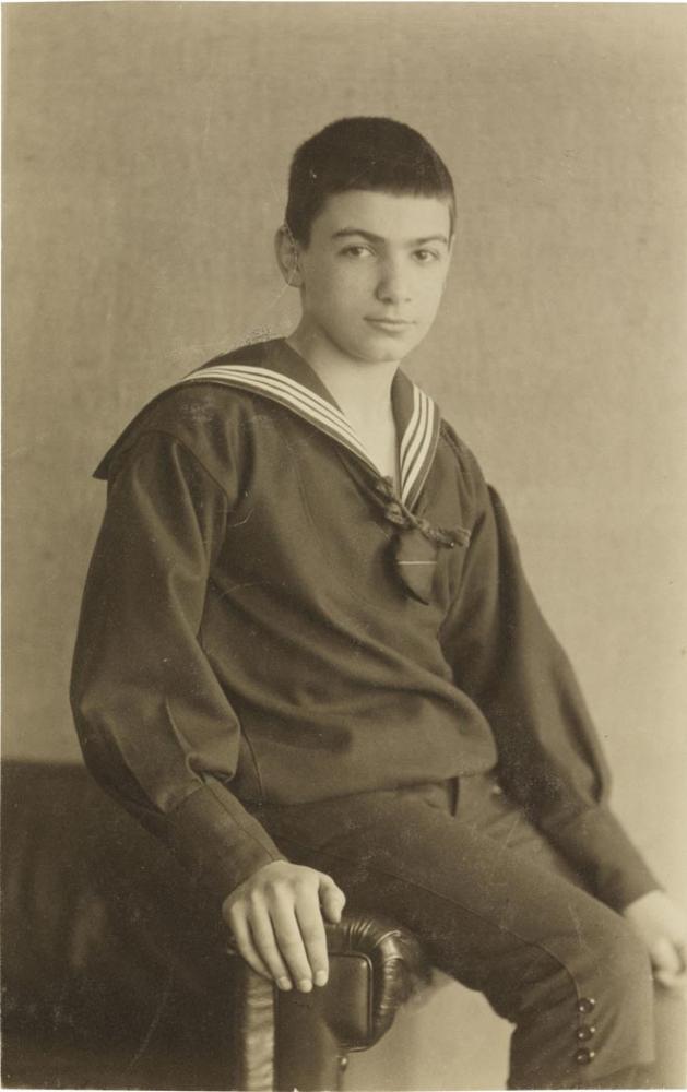 Black-and-white photograph: Sitting boy, studio portrait