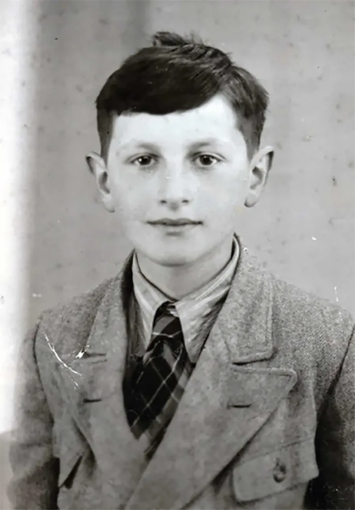Black and white photo: Portrait of a dark-haired boy. He looks friendly into the camera.