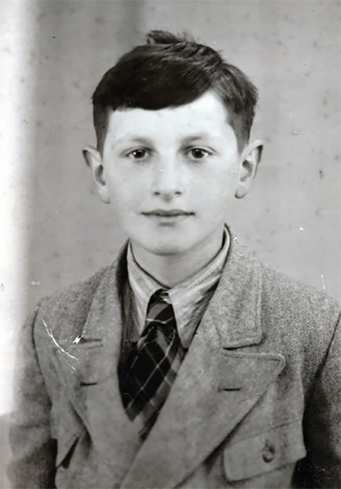 B&W photo: Portrait of a dark-haired boy. He looks friendly into the camera.