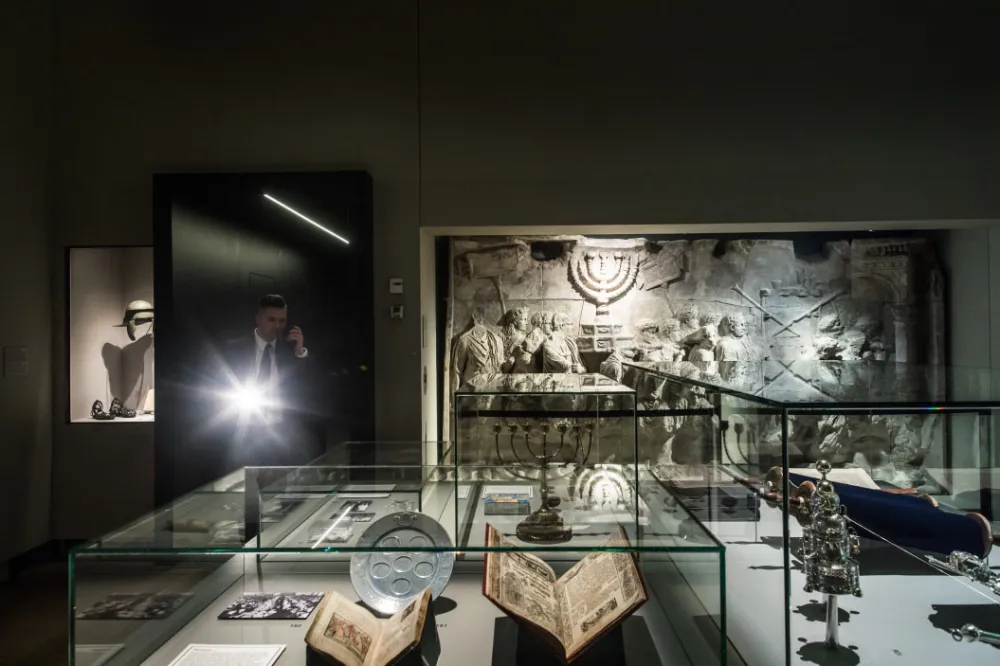 Interior view of an exhibition room, showing a security guard with a flashlight next to the so-called spoils of Jerusalem Relief from the Arch of Titus (original: Rome, 81-96 plaster cast, manufacturer: Virgilio Gherardi, Rome, c. 1900).