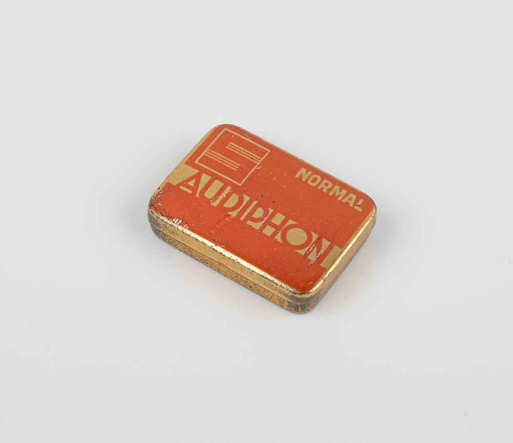 The image shows as golden metal box for gramophone needles of the Audiphon brand of the Schocken department store of ca. 1930.