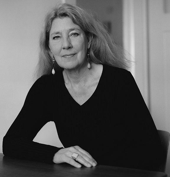 B-W photo: Portrait of a woman with long loose hair. She wears long earrings and looks friendly into the camera.