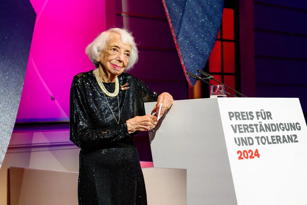Eine Frau steht an einem Podium und lächelt.