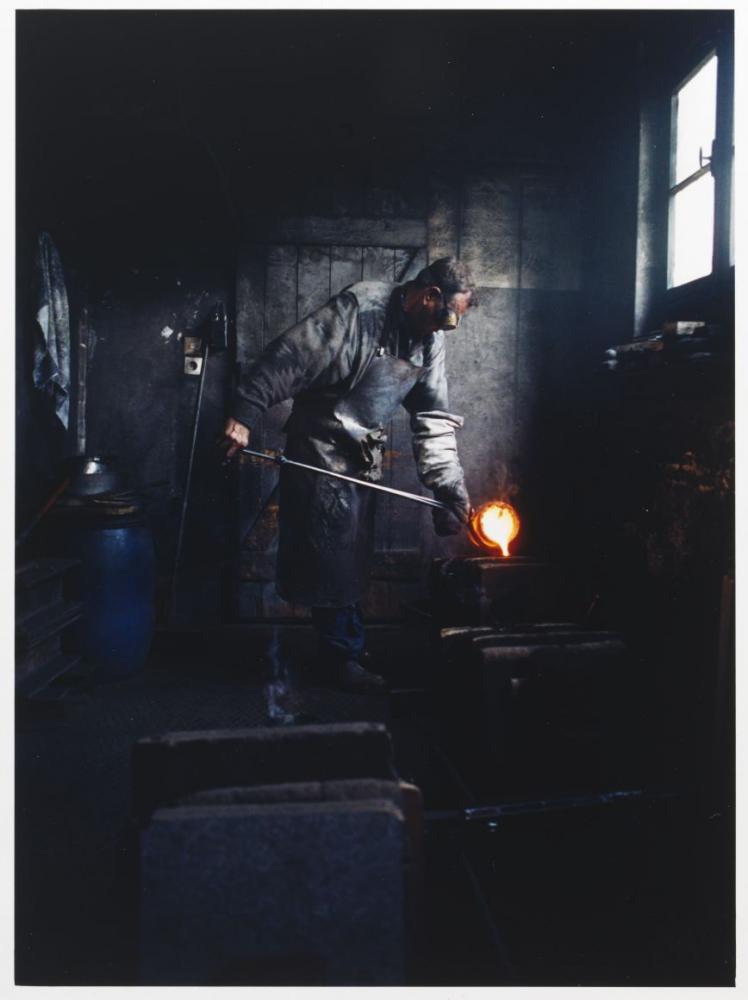 A man pours hot silver into the cavity of the shape of the Hanukkah lamp.