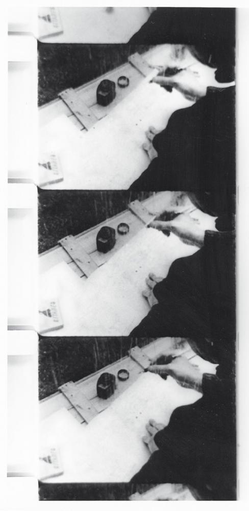 Three film stills in black and white with an inkwell and a hand holding a pen.