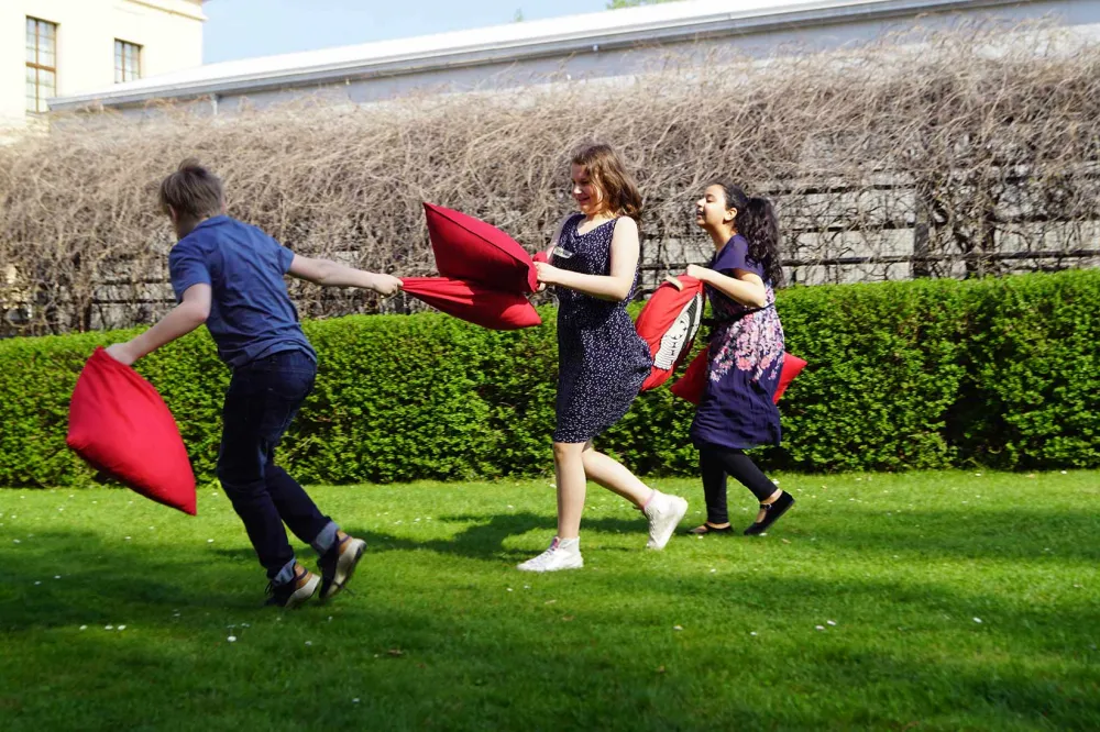 Drei Mädchen bei einer Kissenschlacht im Garten