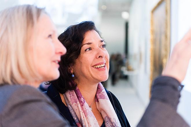 Margret Kampmeyer points to an object outside the image section in the color photograph. Elena Bashkirova looks at the object laughing.