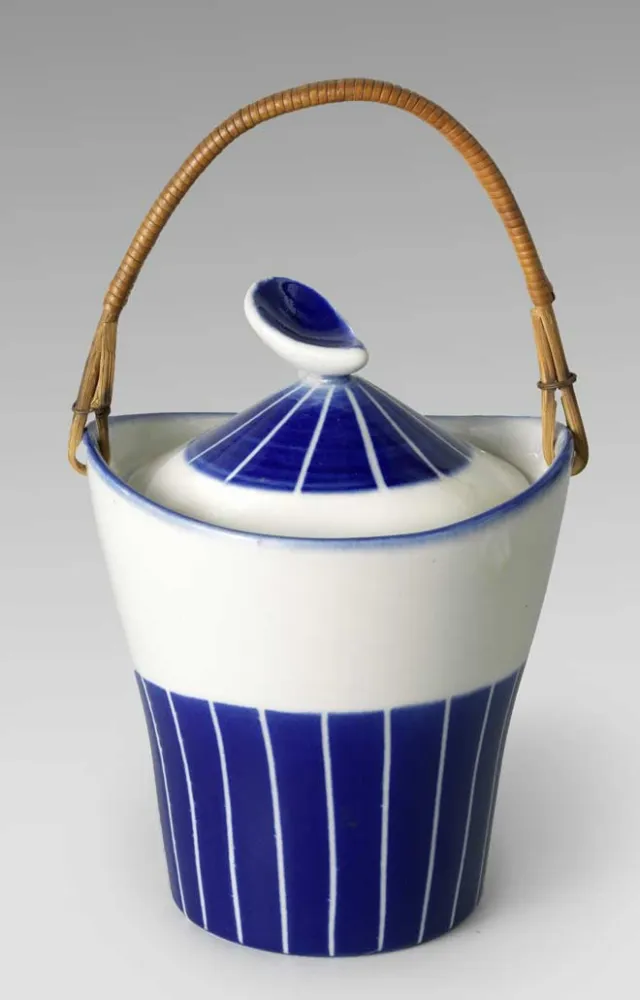 Ceramic blue and white vessel with a stripe pattern and a straw handle