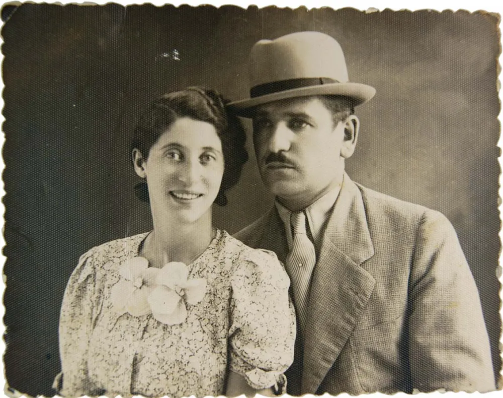 Double black-and-white photographic portrait showing Sally Katz smiling on the left in a floral-patterned dress and Heinrich Katz on the right in a suit and hat.