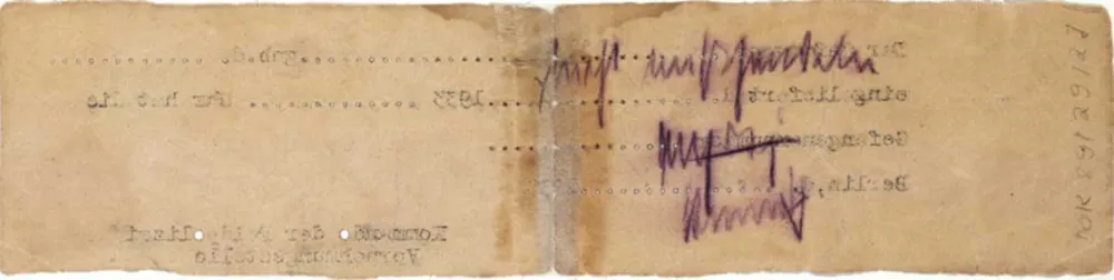 Back of a long, yellowed slip of paper with a handwritten note and a few inverted, typed letters pressed through from the front.