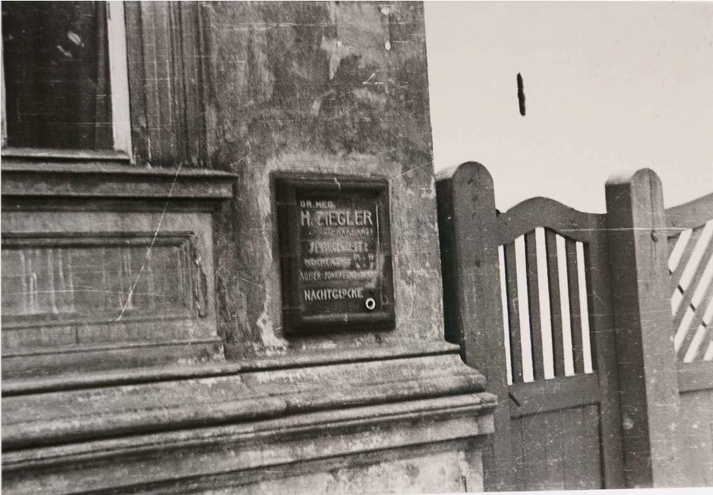 Black and white photograph of a doctor's sign on which the letters are barely visible