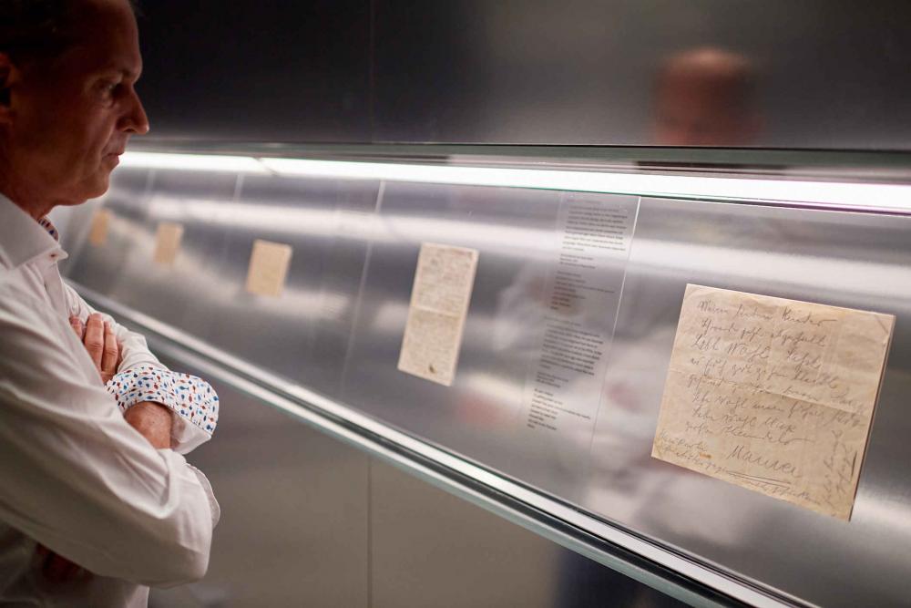 A man stands in front of a showcase with an old letter