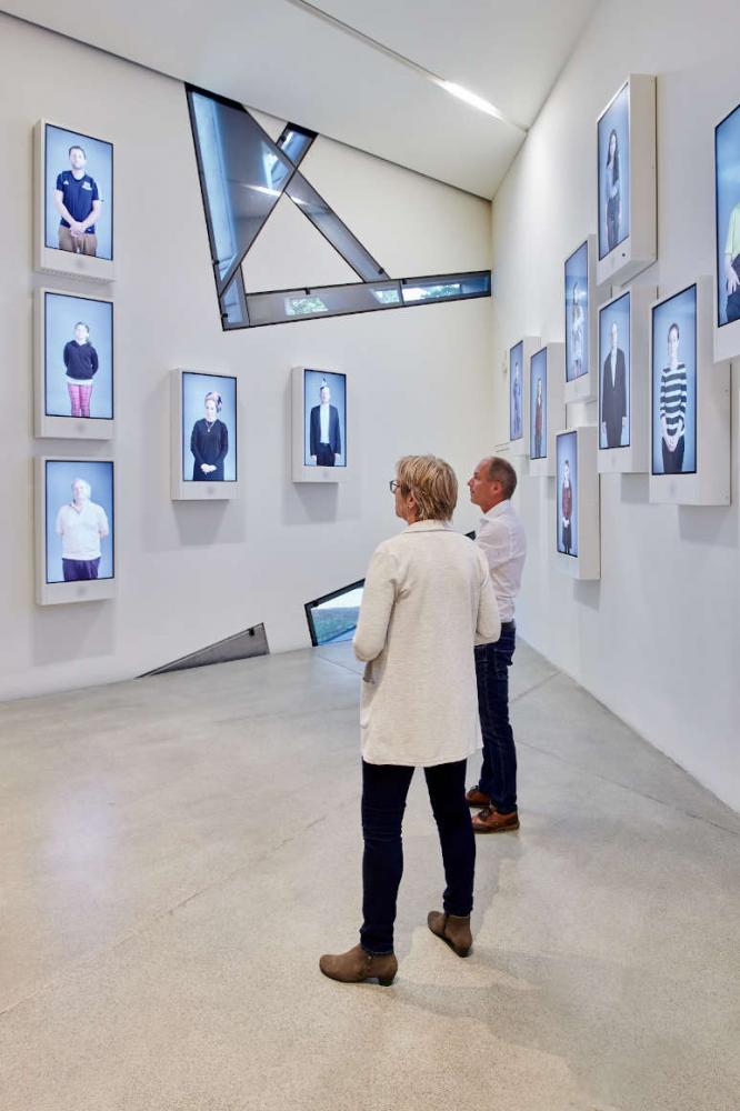 Screens on the wall with people on them, people standing in the room