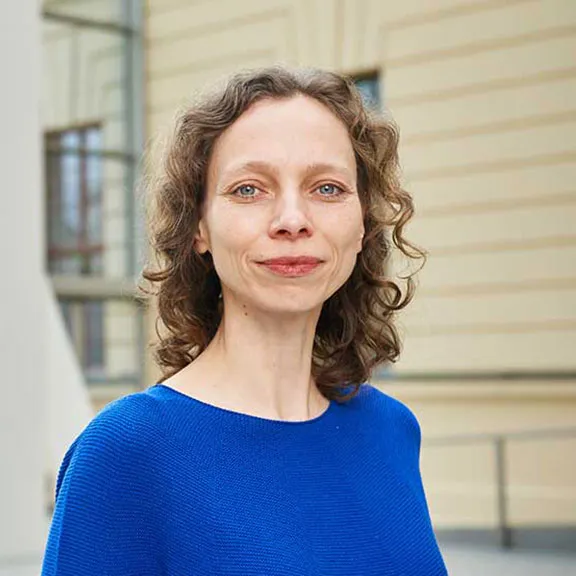 Portrait photo of a smiling woman wearing a bright blue jumper: she looks directly into the camera.